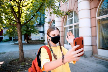 Akıllı telefon kullanan genç kız. Yüz maskesi takan genç kız cep telefonuyla iletişim kuruyor.. 