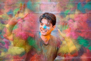 Sokaktaki geleneksel Hint festivali için Holi renkleriyle kaplı genç adam. Renkli yakışıklı adam, dışarıda kameraya bakarak gülen yüz.