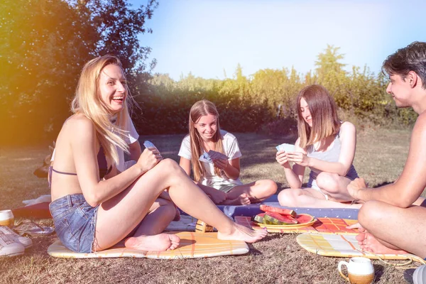 Gençler yaz günü dışarıda piknik yaparken karpuz dilimleriyle tezahürat yapıyorlar. Gençler doğada birlikte eğleniyor, taze meyve yiyorlar.