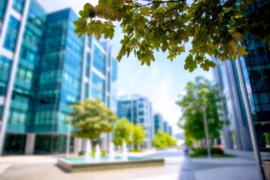 Şehir merkezinde mavi camlı pencereli bulanık lüks bir bina. Kurumsal şehir binaları bulanık arkaplan