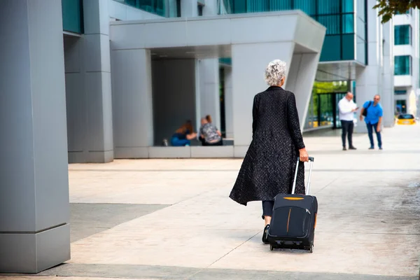 나이든 여자가 공항으로 걸어가고 있습니다 출장가는 — 스톡 사진