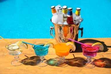 Havuz kenarında renkli kokteyller ve kovada taze şişeler. Havuz barında soğuk içecekler. Boşluğu kopyala
