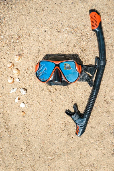 Red half diving scuba mask on beach sand, close up. Recreational sport hobby. Snorkeling and scuba diving concept.