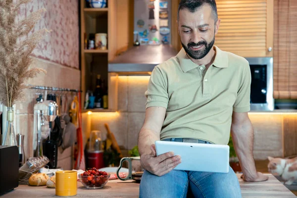 Hombre Barbudo Sentado Mostrador Cocina Mirando Tableta Freelancer Masculino Revisando — Foto de Stock
