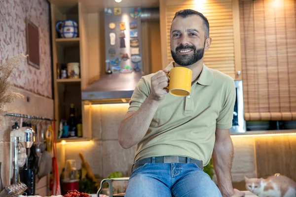 Mature bearded Man drinking coffee in the morning at his kitchen