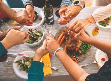 Şükran Günü yemeğinde el ele tutuşup dua etmek. Yemekler için şükran dolu bir aile. Şenlik yemeğinden önce dua ediyorum.