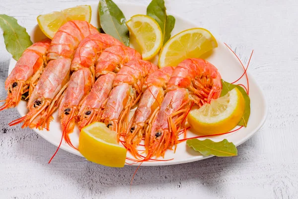 Beyaz arka planda limon ve defne yapraklı pişirilmiş karidesler.