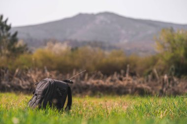 Yakın plan fotoğraf siyah sırt çantası yeşil çimen doğa dağ, bulanık panoramik manzara, gezgin dinlenme tatil konsepti