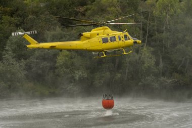 Kova, helikopterdeki yangınla savaşmak için suya batıyor.