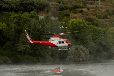 Kova, helikopterdeki yangınla savaşmak için suya batıyor.