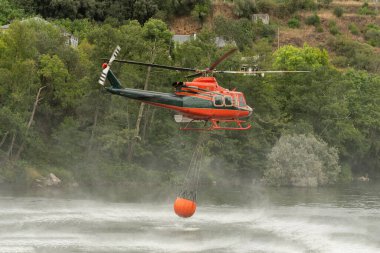 Kova, helikopterdeki yangınla savaşmak için suya batıyor.
