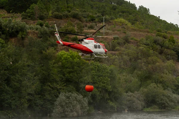 Kova, helikopterdeki yangınla savaşmak için suya batıyor.