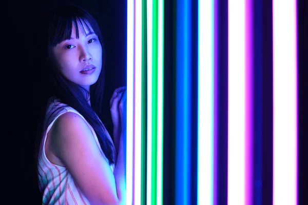 Junge Asiatin posiert mit bunten Neonlichtern im Studio. — Stockfoto