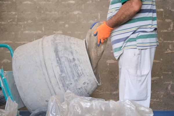 Bouwvakker laadt een zandzak in de betonmixer. — Stockfoto