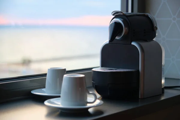 Cafetera y dos tazas listas para usar cerca de una ventana. — Foto de Stock