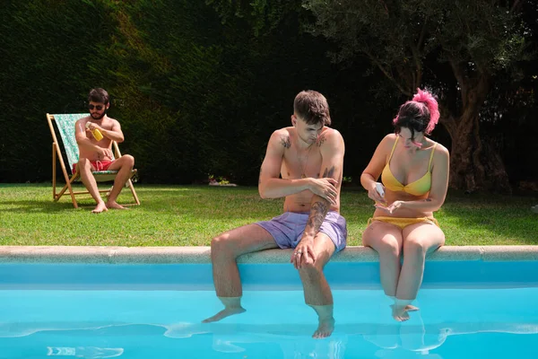 Üç beyaz arkadaş havuz kenarında güneş kremi sürüyor..