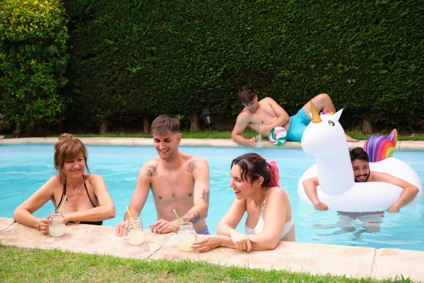Група людей, які п'ють лимонад і розважаються у басейні . — стокове фото