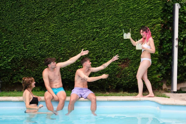 年轻的高加索女人在游泳池里给朋友们端柠檬水. — 图库照片