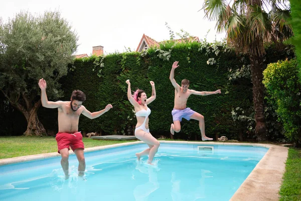 Gruppo di tre amici che saltano in piscina. — Foto Stock