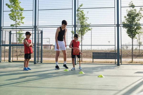 Bambino con una protesi alle gambe che impara a giocare a basket. — Foto Stock