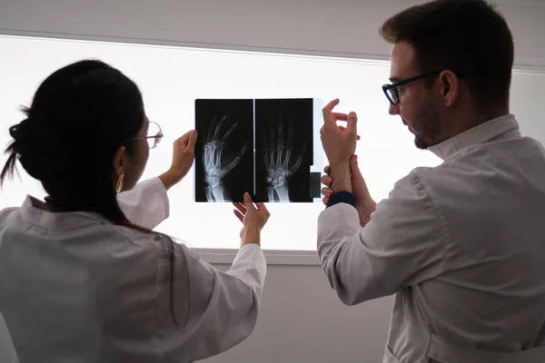 Equipo médico profesional examinando la imagen de rayos X de la mano. Artritis reumatoide. —  Fotos de Stock