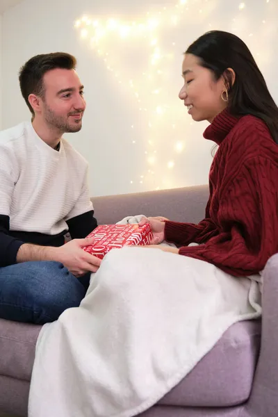 Joven asiático mujer dando un regalo de Navidad a su caucásico novio. — Foto de Stock