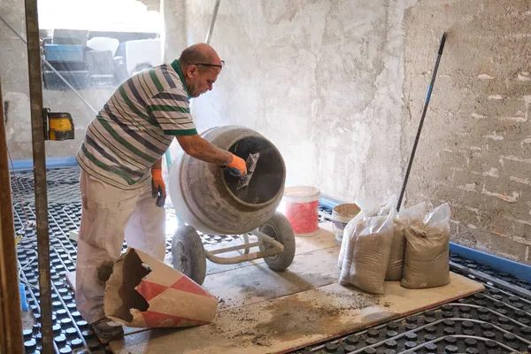 Trabalhador da construção que carrega argamassa de cal no misturador de concreto. — Fotografia de Stock