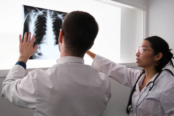 Dos doctores interpretan una imagen de rayos X de costillas. —  Fotos de Stock