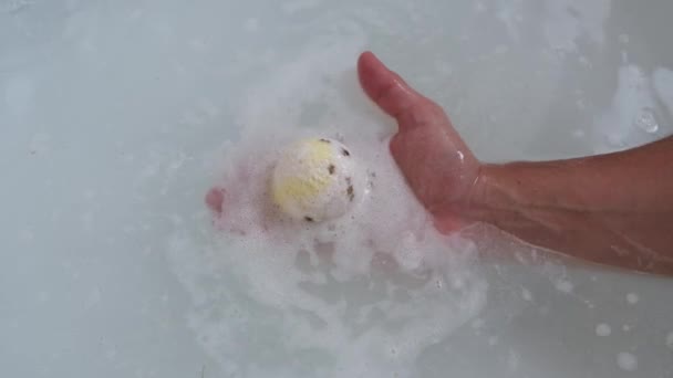Žlutá barva lázně bomba se rozpouští v horké vodě na mužské ruce. — Stock video