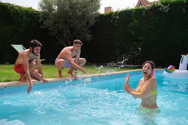 Giovane donna ottenere spruzzato da amici dall'esterno di una piscina. — Foto Stock