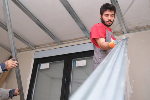 Trabajador agarrando el marco de metal para montar un techo suspendido. —  Fotos de Stock