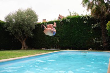 Genç beyaz adam yüzme havuzuna atlıyor..