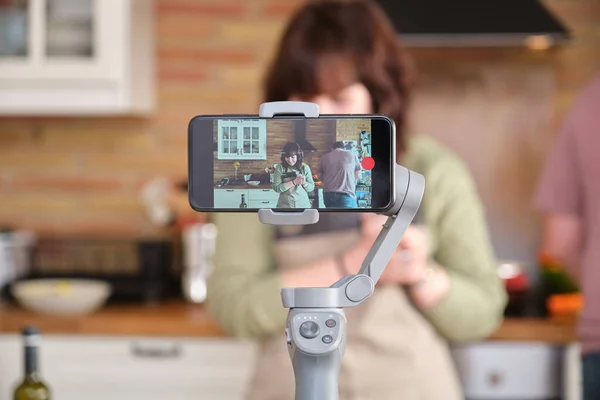 Young woman explaining a recipe and recording a video with her smartphone.