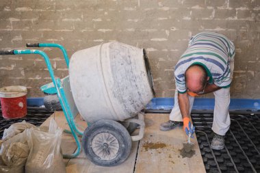 İnşaat işçisi karıştırıcıdaki betonun kalitesini kontrol ediyor..