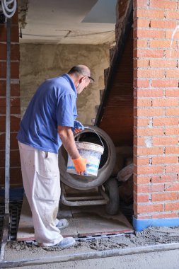 İnşaat işçisi elleri kovaya ile beton mikser yükler.