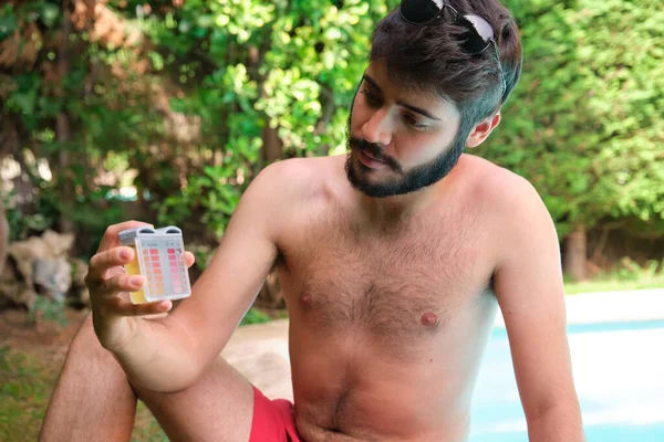 Man checking the ph and cl levels of his swimming pool. — Stock Photo, Image