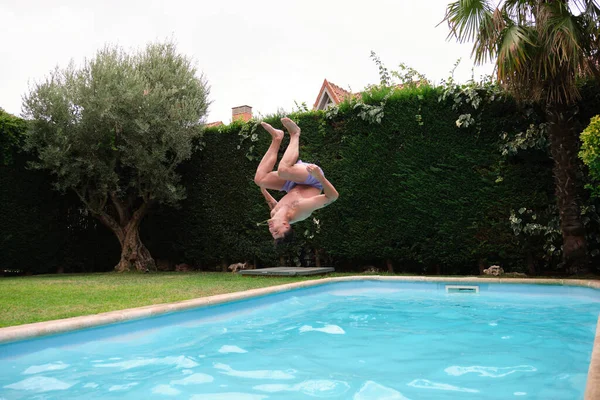 Ung kaukasisk man hoppar i poolen. — Stockfoto