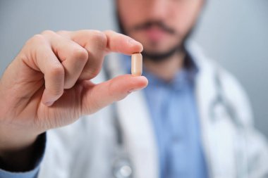 Tanınmayan doktor elinde bir hap tutuyor..