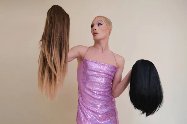 Drag queen person wearing sequined pink dress choosing a wig. — Stock Photo, Image