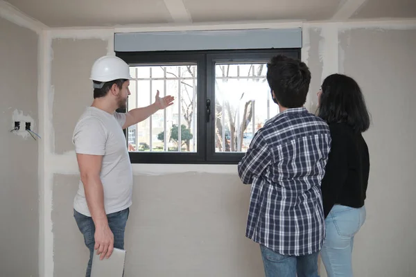 Arquitecto muestra la vista desde la ventana de un nuevo apartamento a una pareja. —  Fotos de Stock