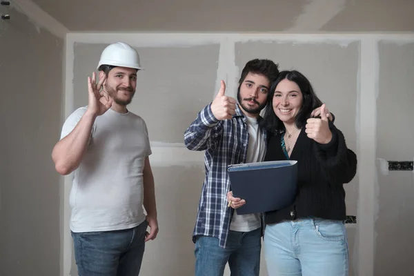 Young couple and architect celebrate the signing of the contract to buy a house. — Stock Photo, Image