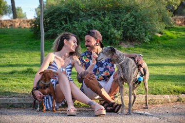 Genç, dövmeli bir çift köpekleriyle sarılıp oturuyor..