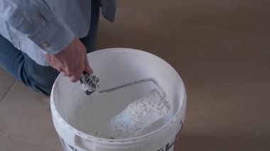 Profesyonel işçinin yakın plan beyaz boya kovasına boya silindiri batırması..