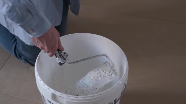Close up of professional workman soaking paint roller into white paint bucket. — Vídeo de Stock