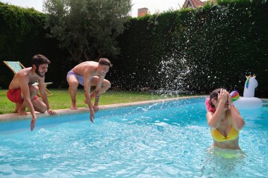 Genç bir kadın yüzme havuzunun dışından arkadaşları tarafından su sıçratılıyor..
