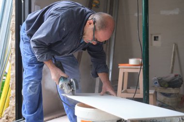 Profesyonel tiler radyal testereyle beyaz seramik fayans kesiyor..