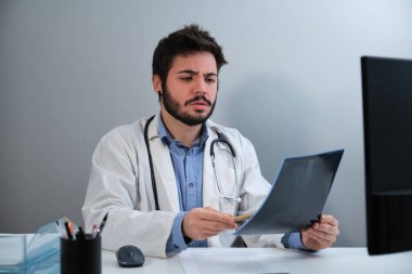 Young doctor looking amazed at a X-ray of a pelvis and spinal column.