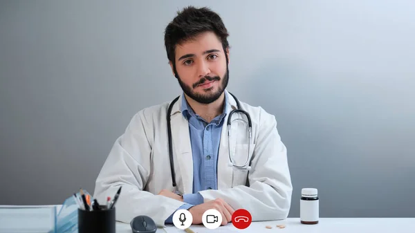 Laptop videocall screenshot of a young doctor looking at camera and smiling. — Stok fotoğraf