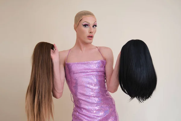 Drag queen person wearing sequined pink dress choosing a wig. — Stock Photo, Image