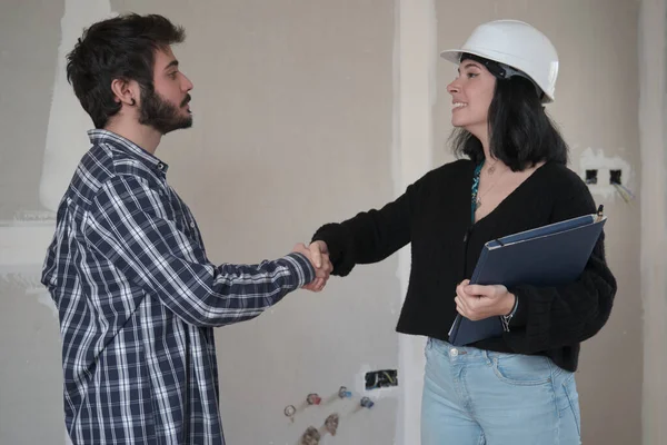 Hombre y mujer arquitecto estrechando las manos después de la firma del contrato de compra de la casa. — Foto de Stock